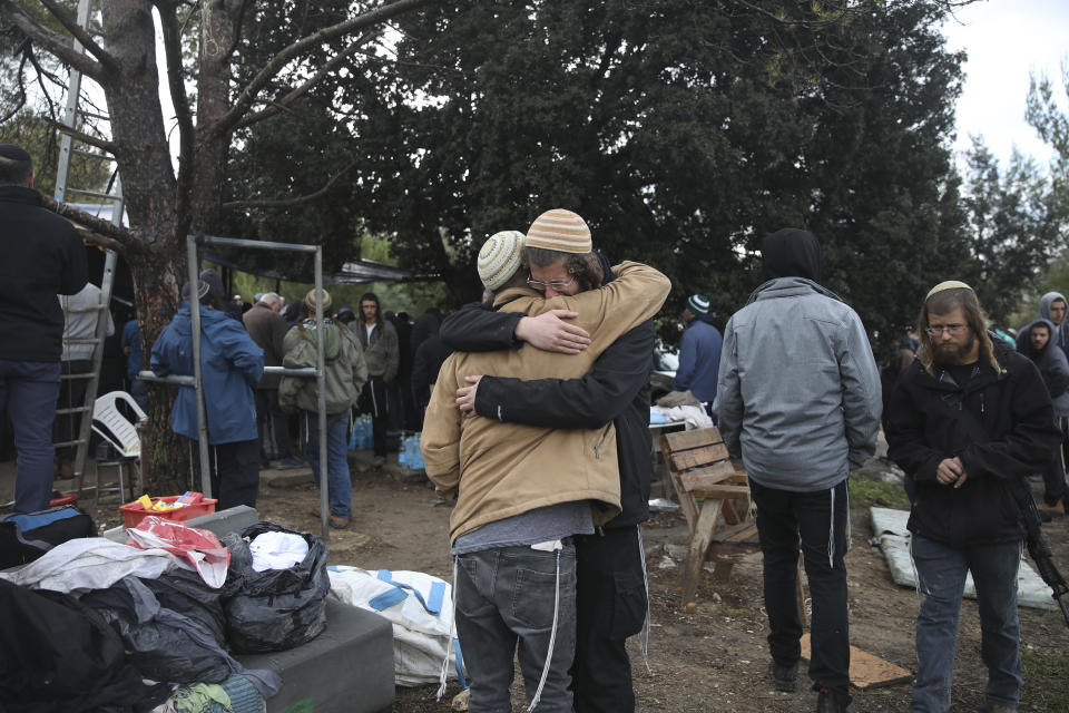 Mourners hug during the funeral of Yehuda Dimentman, 25, who was killed in a shooting attack by a Palestinian gunman near the Jewish outpost of Homesh in the West Bank, Friday, Dec. 17, 2021. At least one Palestinian gunman opened fire Thursday night at a car filled with Jewish seminary students next to a West Bank settlement outpost, killing an Israeli man and lightly wounding two other people, Israeli officials said. (AP Photo/Moti Milrod)