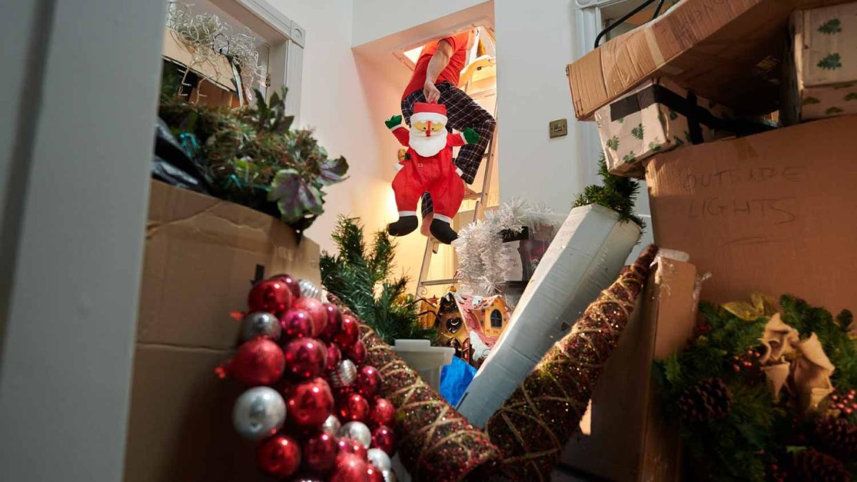 Man putting christmas back in the attic