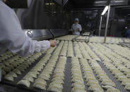 In this July 18, 2018, photo, workers inspect dumplings on a conveyor belt that are made at an automated factory of CJ CheilJedang Corp. in Incheon, South Korea. South Korea’s largest food company is making a multimillion-dollar bet on “mandu,” developing its own machines to automate the normally labor-intensive production of the Korean dumpling and building factories around the world.(AP Photo/Lee Jin-man)