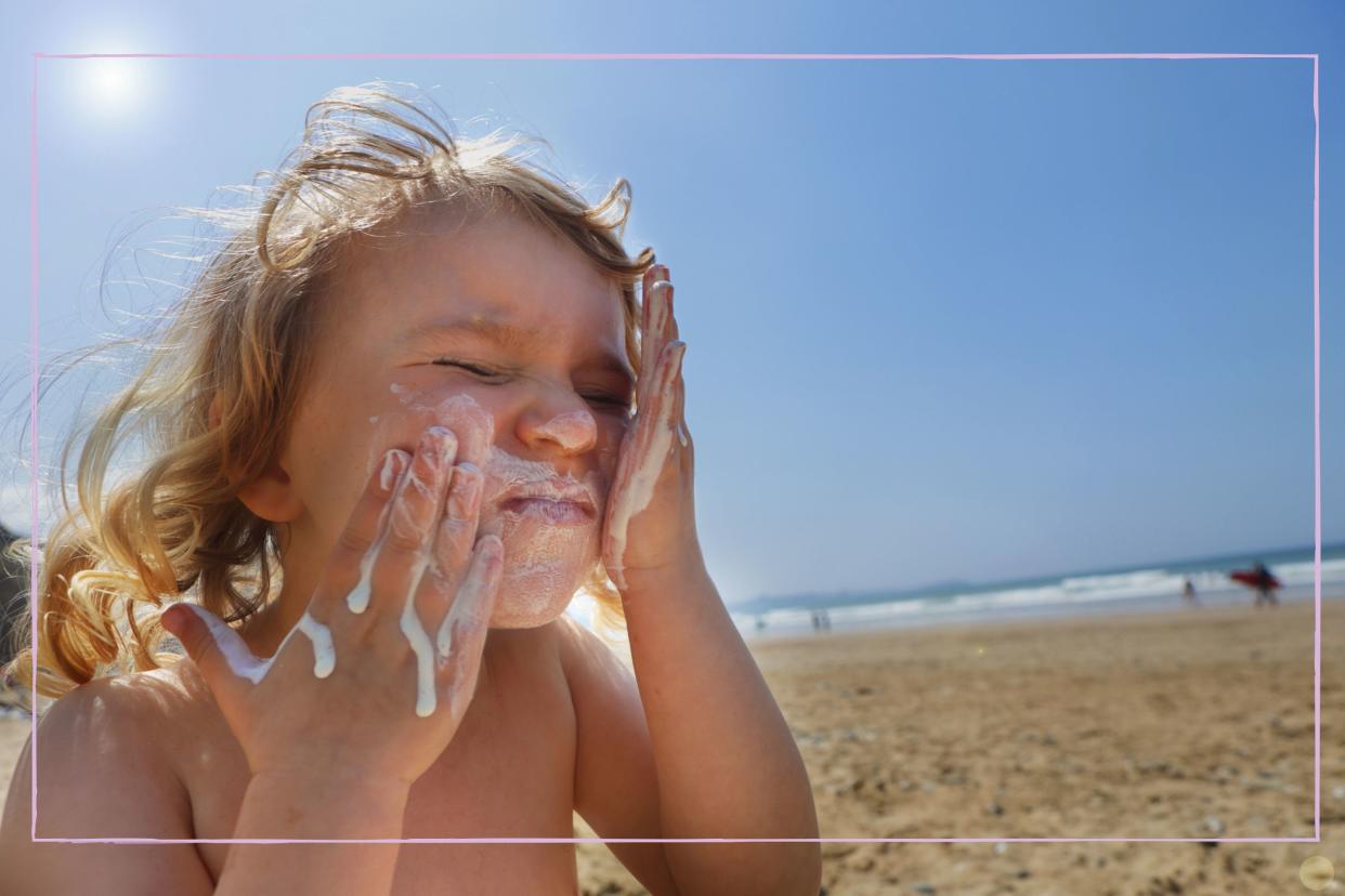  Child applying sun cream to their face. 