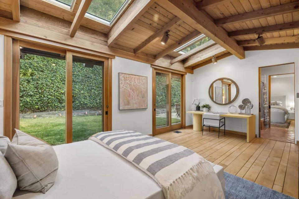 Large contemporary bedroom in Emma CHamberlain's LA home, complete with skylights and sliding doors leading to the backyard.