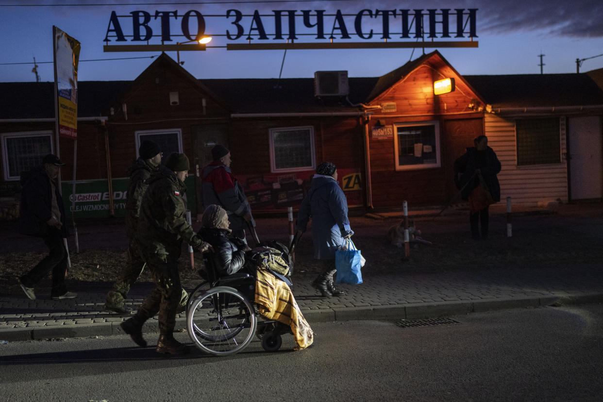 Poland's soldier helps a refugee who fled the war from Ukraine at the Medyka border crossing in Poland, on Saturday, March 12, 2022. (AP Photo/Petros Giannakouris)