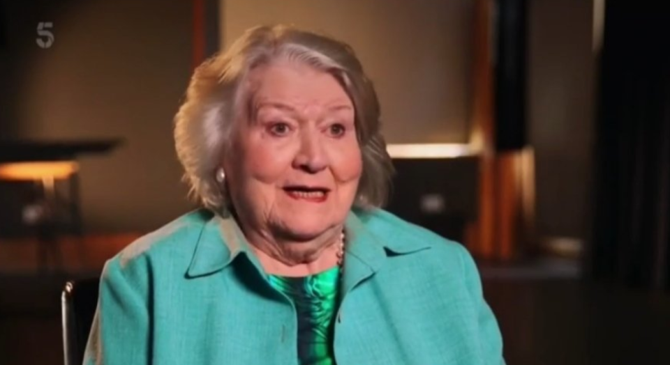 Patricia Routledge wears a teal jacket as she speaks in a documentary. 