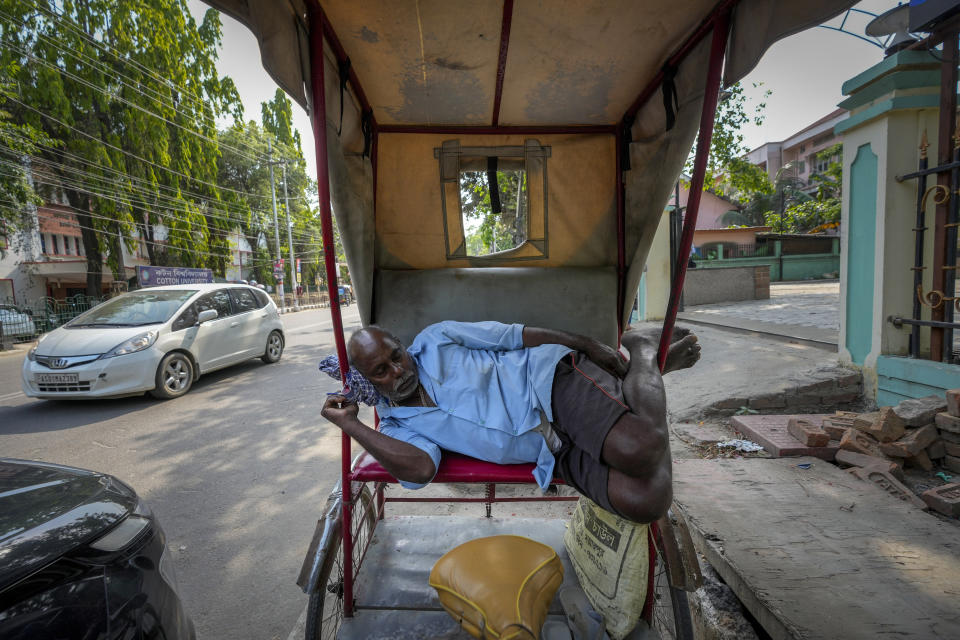 A rickshaw puller sleeps in the shade of a tree on a hot summer afternoon in Guwahati, India, Friday, May 3, 2024. (AP Photo/Anupam Nath)