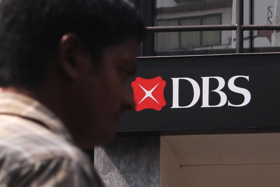 A man walks past a Development Bank of Singapore(DBS) logo.