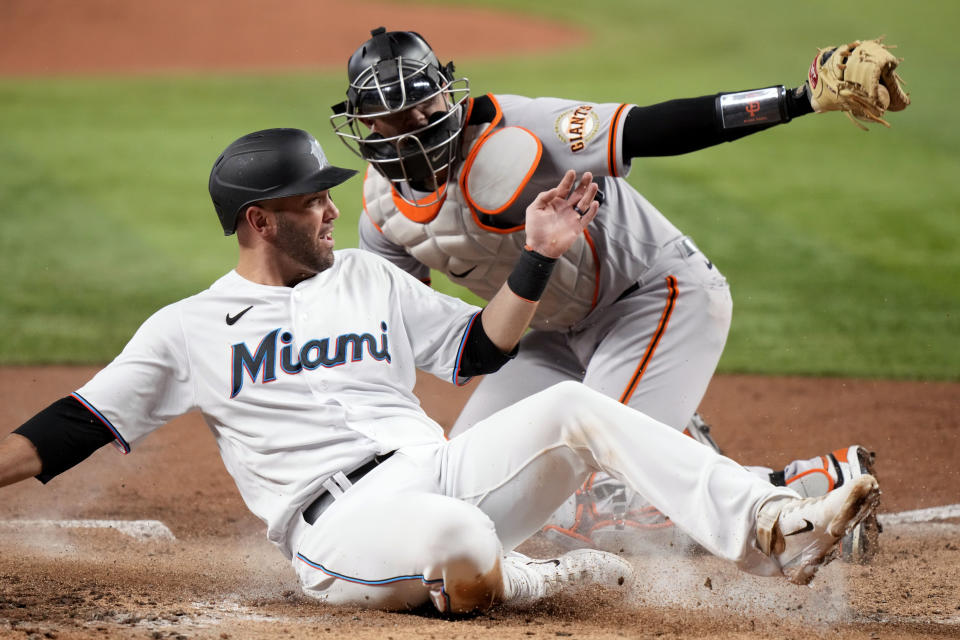 Miami Marlins' Jacob Stallings, left, scores past San Francisco Giants catcher Blake Sabol during the third inning of a baseball game, Tuesday, April 18, 2023, in Miami. (AP Photo/Lynne Sladky)