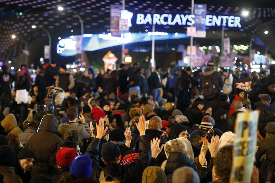 Protesters rallying against a grand jury's decision not to indict the police officer involved in the death of Eric Garner hold their hands up symbolically as they observe a moment of silence at the intersection of Flatbush Avenue and Atlantic Avenue near the Barclays Center, Thursday, Dec. 4, 2014, in the Brooklyn borough of New York. A grand jury cleared a white New York City police officer Wednesday in the videotaped chokehold death of Garner, an unarmed black man, who had been stopped on suspicion of selling loose, untaxed cigarettes. (AP Photo/Jason DeCrow)