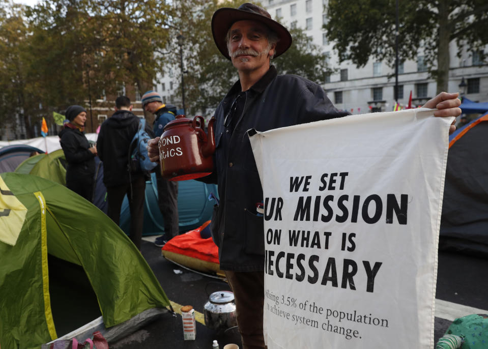 A climate change protester holds up his banner on Whitehall in London, Tuesday, Oct. 8, 2019. Police are reporting they have arrested more than 300 people at the start of two weeks of protests as the Extinction Rebellion group attempts to draw attention to global warming.(AP Photo/Alastair Grant)