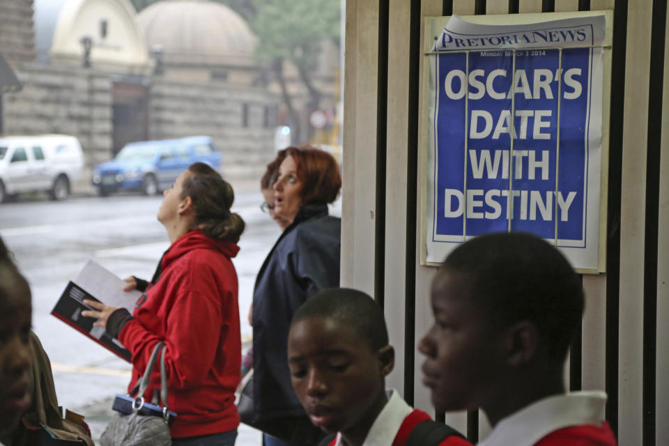 People stand around a newspaper poster reading "Oscar's date with destiny" before Oscar Pistorius arrives at the high court in Pretoria, South Africa, Monday, March 3, 2014. Pistorius is charged with premeditated murder for the shooting death of his girlfriend, Reeva Steenkamp, on Valentine's Day in 2013. (AP Photo/Schalk van Zuydam)