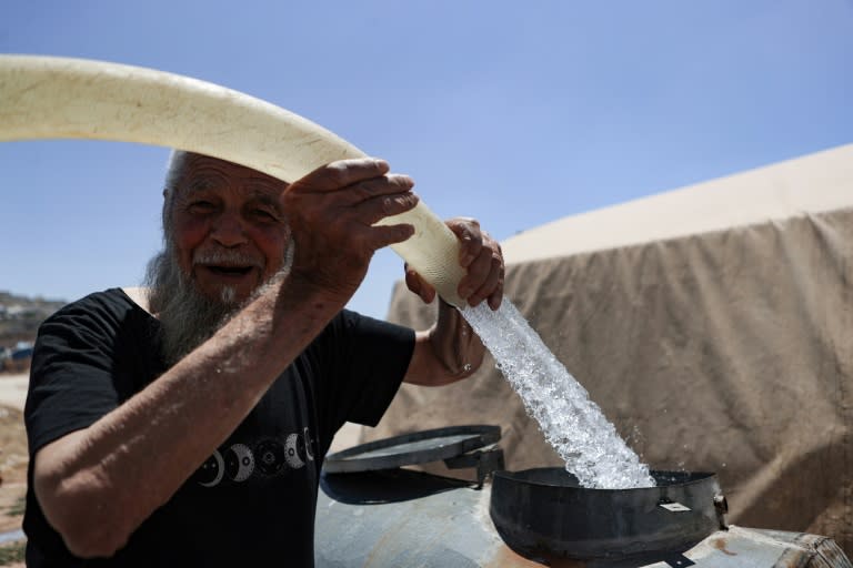 A man fills barrels with water at a camp for internally displaced people in northern Syria (AAREF WATAD)