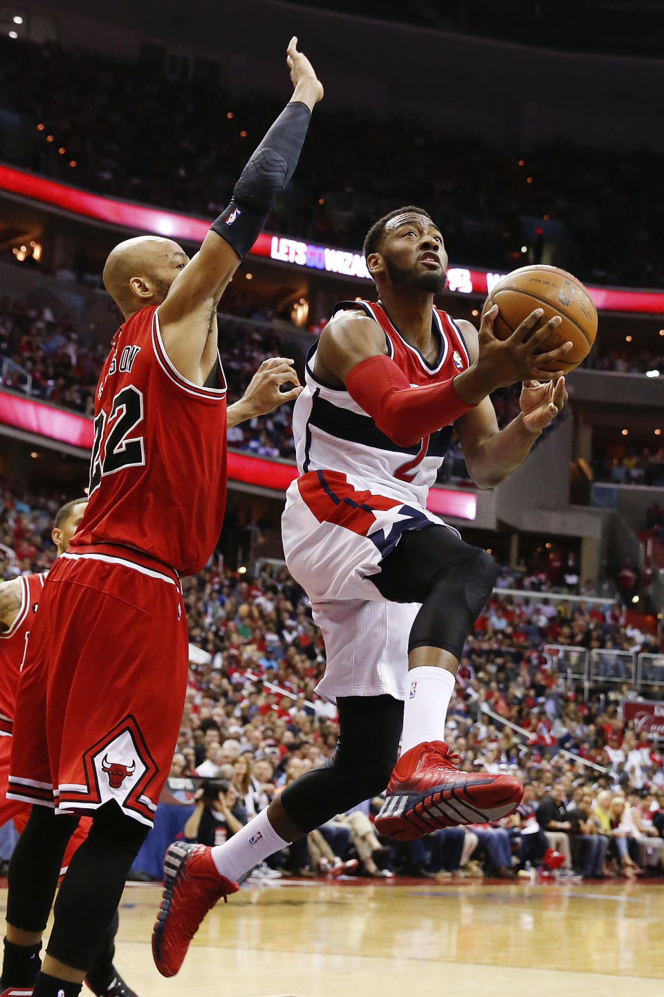 Washington Wizards guard John Wall (2) shoots under pressure from Chicago Bulls forward Taj Gibson (22) during the second half in Game 4 of an opening-round NBA basketball playoff series in Washington, Sunday, April 27, 2014. (AP Photo/Alex Brandon)