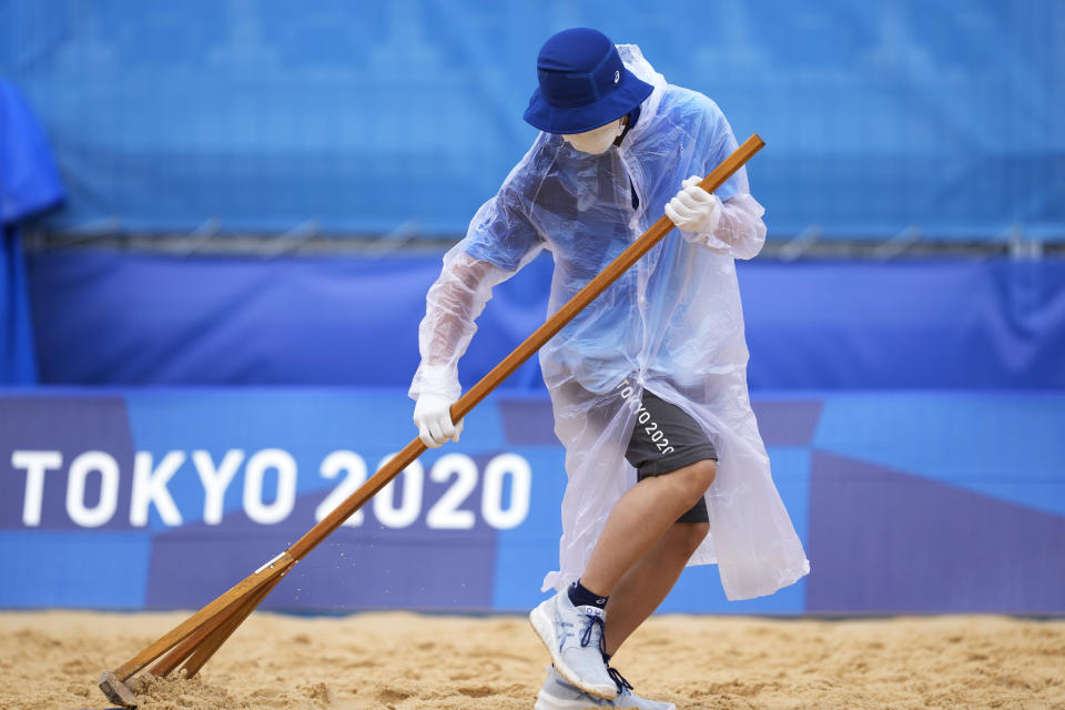 A member of the grounds crew rakes the sand before a men's beach volleyball match at the 2020 Summer Olympics, Tuesday, July 27, 2021, in Tokyo, Japan. (AP Photo/Petros Giannakouris)