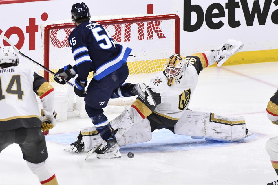 Vegas Golden Knights goaltender Laurent Brossoit (39) makes a save against Winnipeg Jets' Mark Scheifele (55) during first-period Game 4 NHL Stanley Cup first-round hockey playoff action in Winnipeg, Manitoba, Monday April 24, 2023. (Fred Greenslade/The Canadian Press via AP)