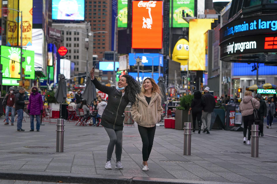 Pedestrians pose for pictures in Times Square, Monday, Nov. 15, 2021, in New York. Even as visitors again crowd below the jumbo screens in New York’s Times Square, the souvenir shops, restaurants, hotels and entrepreneurs within the iconic U.S. landmark are still reeling from a staggering pandemic. (AP Photo/Seth Wenig)