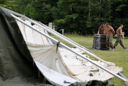 Members of the Canadian Armed Forces carry cots to the newly erected tents they assembled to help deal with the influx of asylum seekers near the border in Lacolle, Quebec, Canada August 10, 2017. REUTERS/Christinne Muschi