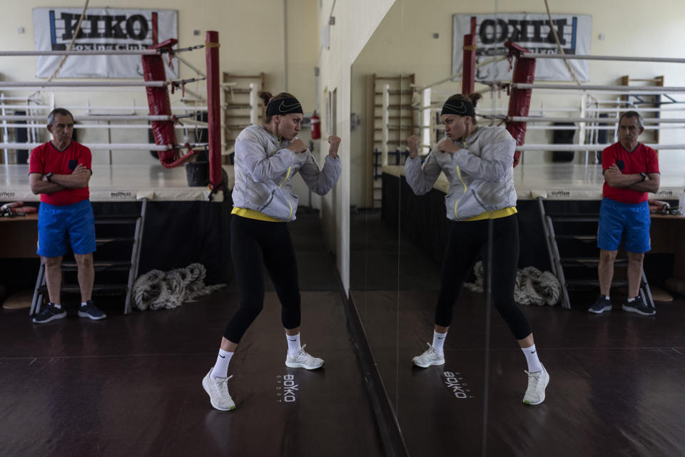 La boxeadora ucraniana Anna Lysenko hace sombra, el jueves 6 de julio de 2023, ante la mirada de su entrenador, Oleksandr Salenko, en el Kiko Boxing Club de Kiev, Ucrania. (AP Foto/Jae C. Hong)