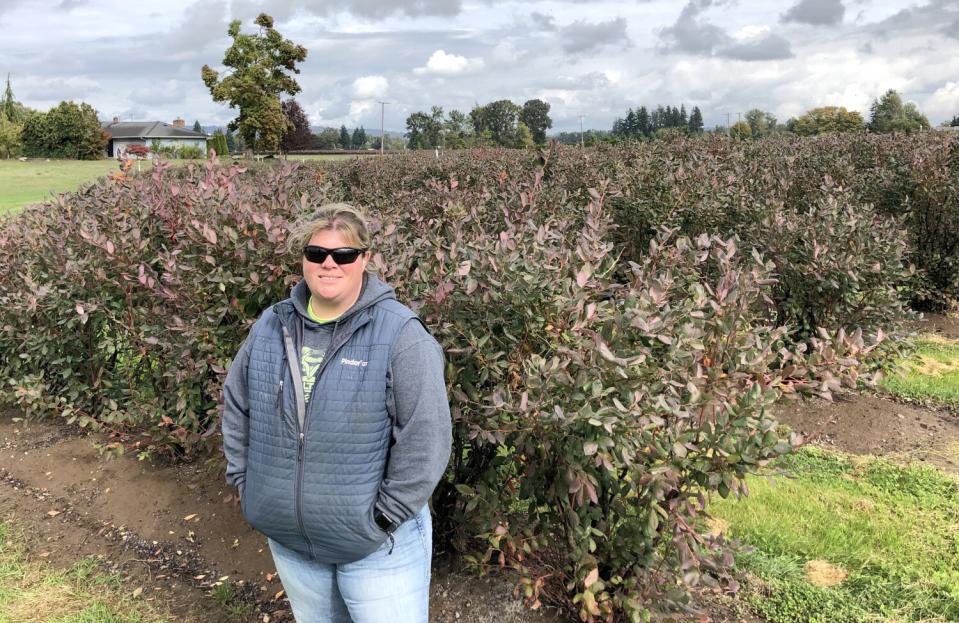 Anne Krahmer-Steinkamp stands outside in front of bushes