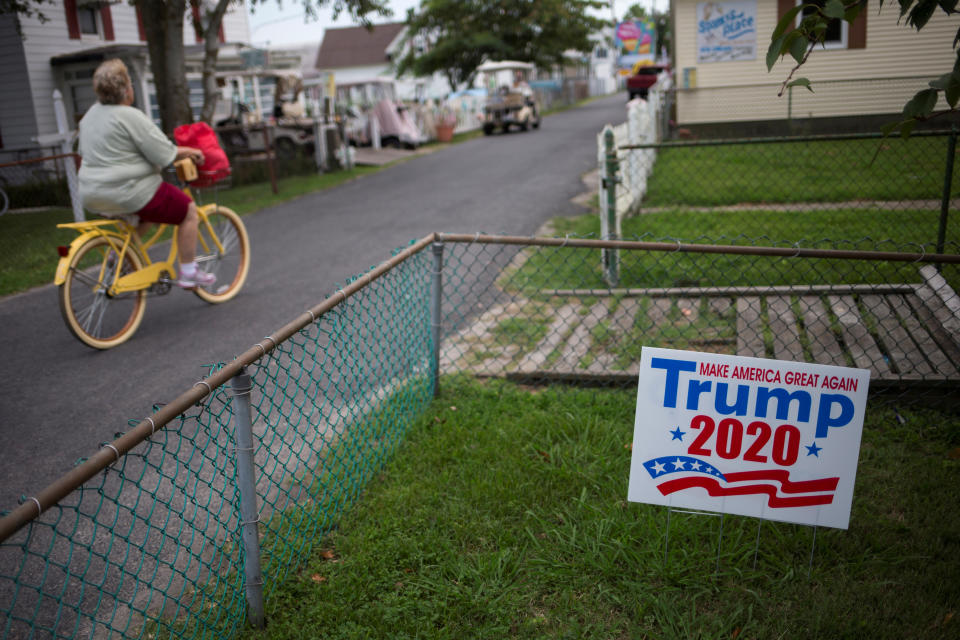 A woman cycles past a house displaying a sign supporting U.S. President Donald Trump on Tangier Island, Virginia (REUTERS/Adrees Latif)