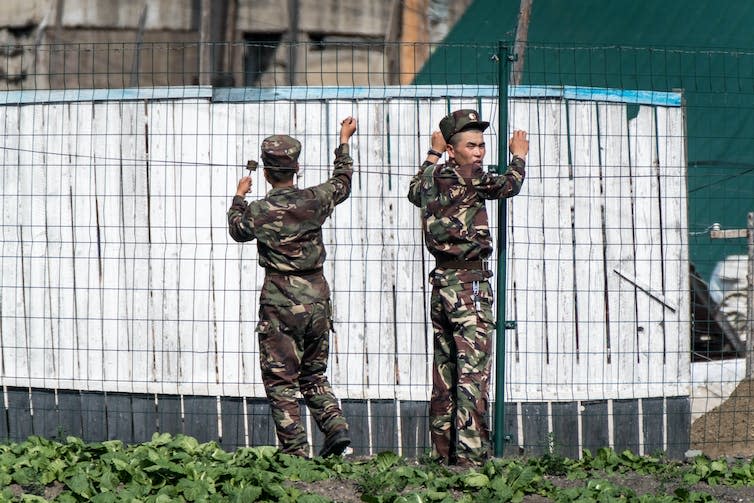 North Korean soldiers guarding a border fence.