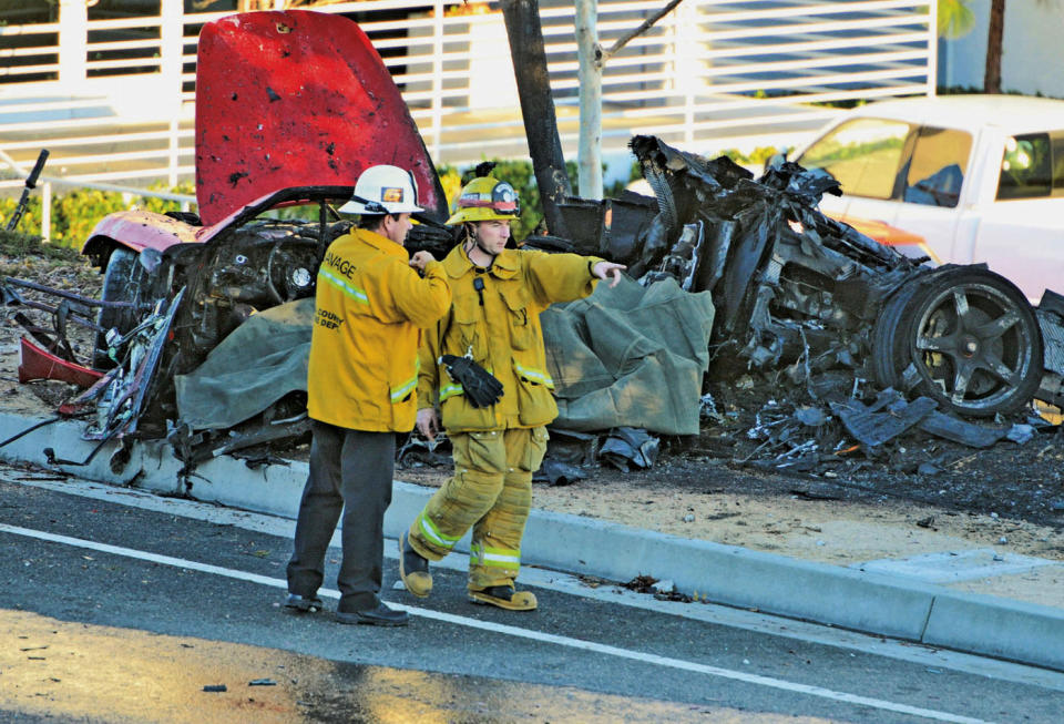 FILE - In this Nov. 30, 2013, file photo, sheriff's deputies work near the wreckage of a Porsche that crashed into a light pole on Hercules Street near Kelly Johnson Parkway in Valencia, Calif. A coroner's report says the Porsche carrying "Fast & Furious" star Paul Walker may have been going 100 mph or more before it crashed, killing both Walker and the driver. The report released Friday, Jan. 3, 2014, by the Los Angeles County coroner's office says that Roger Rodas, Walker's friend and financial adviser, was driving the 2005 Porsche Carrera GT at an unsafe speed, estimated by witnesses to be 100 mph or more. (AP Photo/The Santa Clarita Valley Signal, Dan Watson, File)