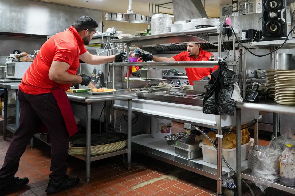 Chef Vicente Vargas, left, passes Ricky Vargas a bowl.