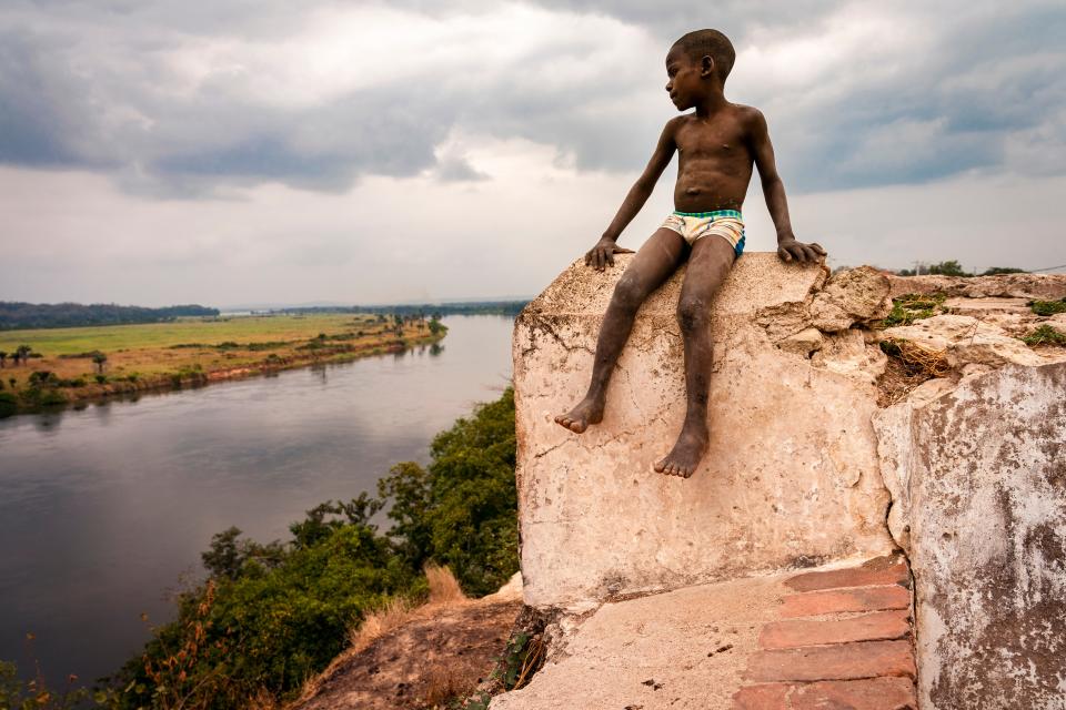 A boy looks out toward the Kwanza river from the Fortaleza de Massangano in Angola. The fort was a base of operations for the Portuguese. Captured Africans were branded and baptized before being taken to the coast and loaded onto slave ships.