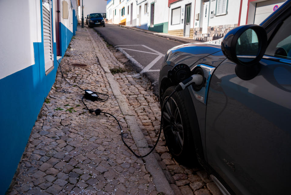 Vila do Bispo, Portugal. October 2020. Electric car charging on the street. Cable from the house.