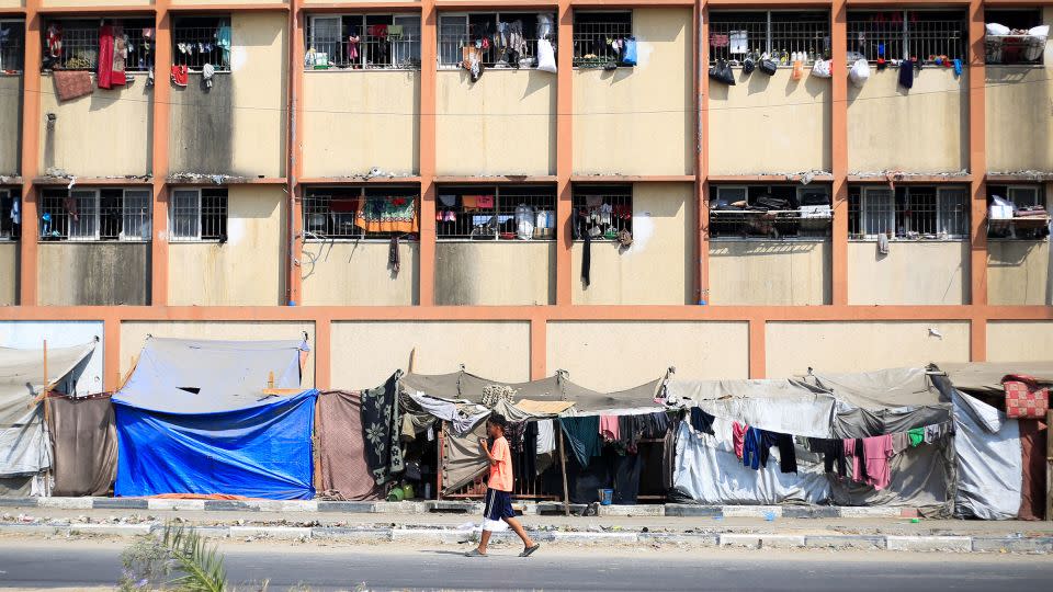 A Palestinian boy walks in front of a school used as a shelter by displaced people in Deir al-Balah. - Eyad Baba/AFP/Getty Images