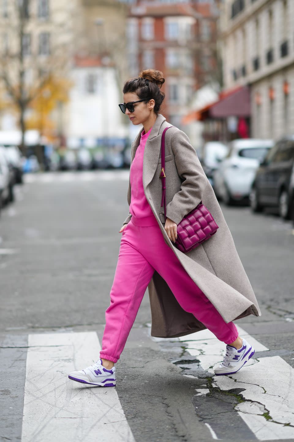 paris, france december 11 katie giorgadze katieone wears a black sunglasses, a neon pink recycled cotton sweater, matching neon pink recycled cotton sport pants jogger pants, a purple shiny leather padded cassette shoulder bag from bottega veneta, a pale brown wool long coat, white leather and purple details 550 sneakers from new balance, during a street style fashion photo session, on december 11, 2021 in paris, france photo by edward berthelotgetty images