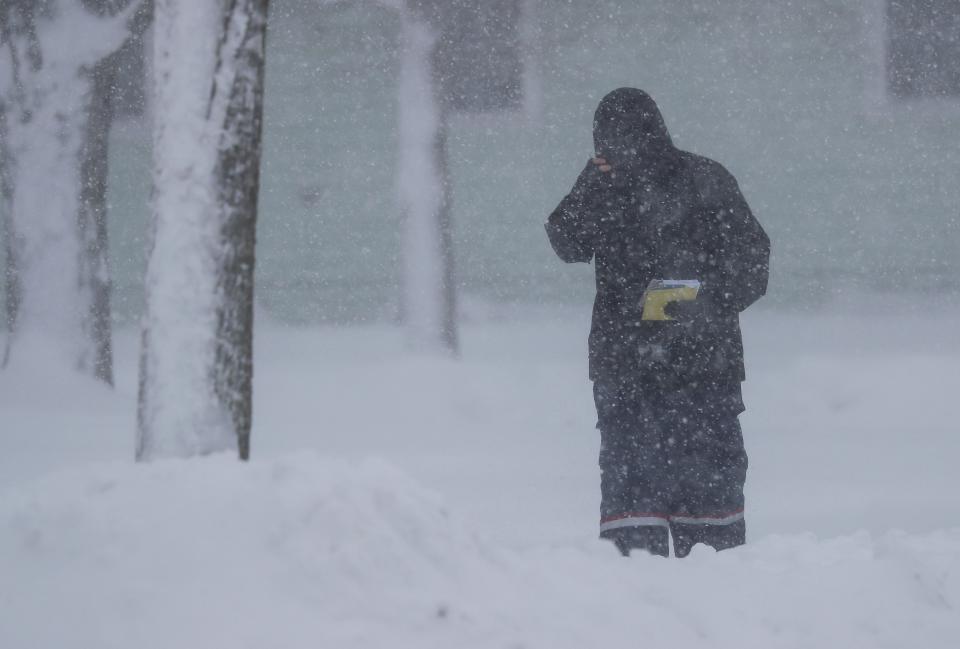 Postal worker Zach Owen works in blizzard-like conditions Friday in Green Bay. The area is under a blizzard warning through noon Saturday.