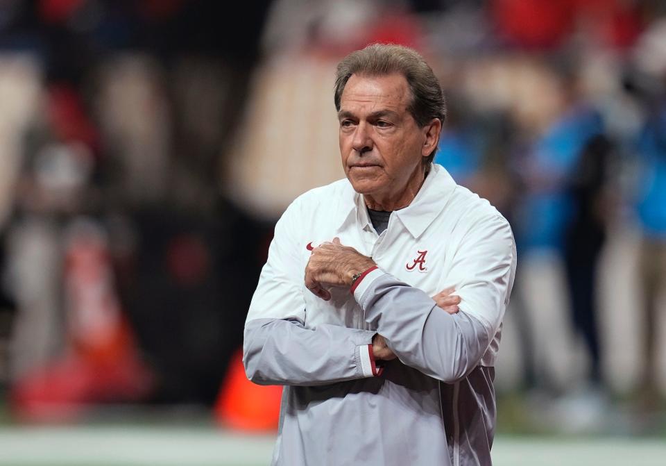 Nick Saban stands with his arms folded while on the field in 2021.