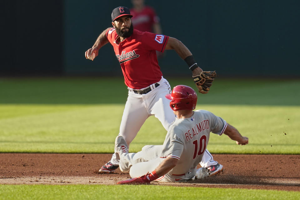 Cleveland Guardians shortstop Amed Rosario, top, throws to first base after forcing out Philadelphia Phillies' J.T. Realmuto (10) at second base in the second inning of a baseball game on a ball hit by Phillies' Bryson Stott who was safe at first base Saturday, July 22, 2023, in Cleveland. (AP Photo/Sue Ogrocki)