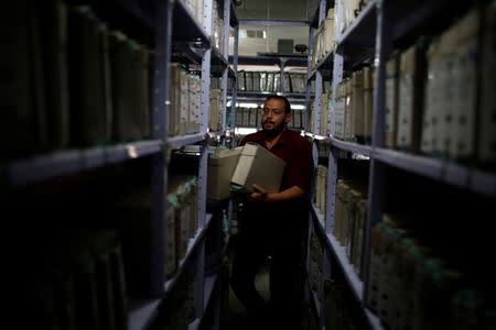 A Palestinian employee carries land registry files at Gaza Land Authority, in Gaza City June 19, 2018. Picture taken June 19, 2018. REUTERS/Mohammed Salem