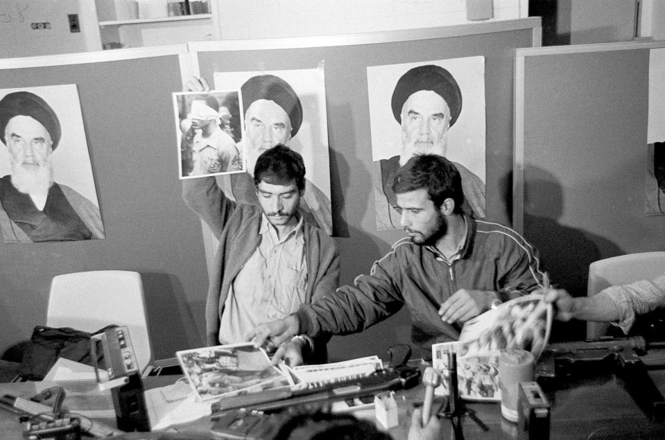 FILE - In this Nov. 5, 1979, file photo, Ebrahim Asgharzadeh, left, a representative of the Iranian students who stormed the U.S. Embassy on Nov. 4, holds up a portrait of one of the blindfolded hostages, during a news conference in the embassy in Tehran. Posters of the Islamic Revolution leader Ayatollah Ruhollah Khomeini adorn the wall. The man at right is unidentified. Speaking to The Associated Press ahead of the 40th anniversary of the attack, Asgharzadeh acknowledged that the repercussions of the crisis still reverberate as tensions remain high between the U.S. and Iran over Tehran’s collapsing nuclear deal with world powers. (AP Photo/File)