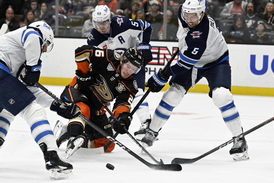 Anaheim Ducks left wing Brock McGinn (26) vies for the puck with Winnipeg Jets left wing Alex Iafallo, left, center Mark Scheifele (55) and defenseman Brenden Dillon (5) during the second period of an NHL hockey game in Anaheim, Calif., Sunday, Dec. 10, 2023. (AP Photo/Alex Gallardo)