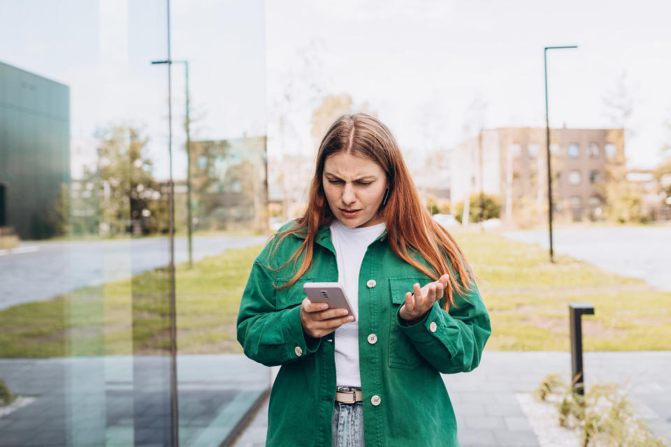 A woman looking confused at her phone