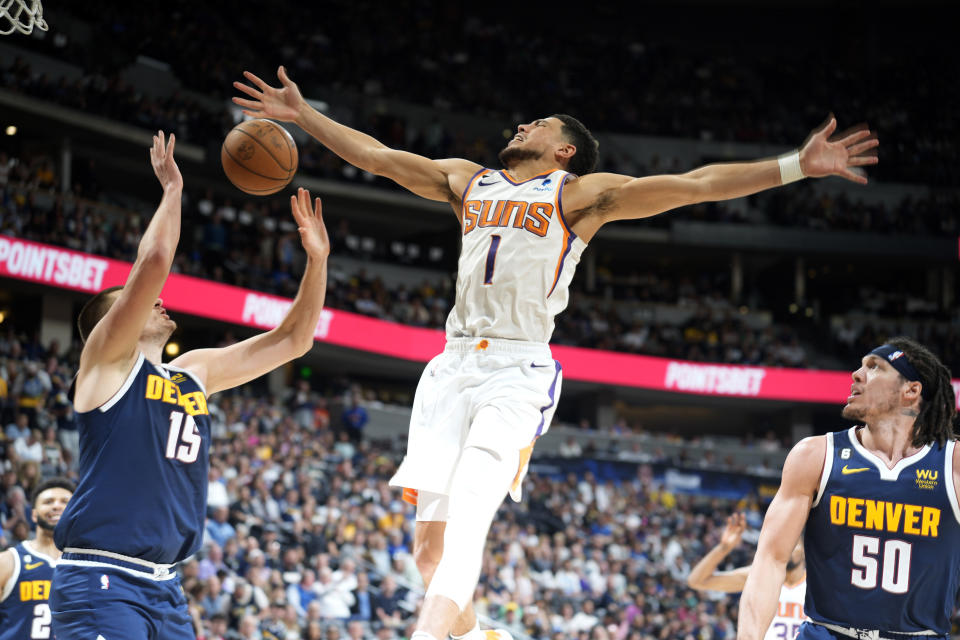 Phoenix Suns guard Devin Booker, center, loses control of the ball while driving to the rim between Denver Nuggets center Nikola Jokic, left, and forward Aaron Gordon in the second half of Game 2 of an NBA second-round playoff series Monday, May 1, 2023, in Denver. (AP Photo/David Zalubowski)