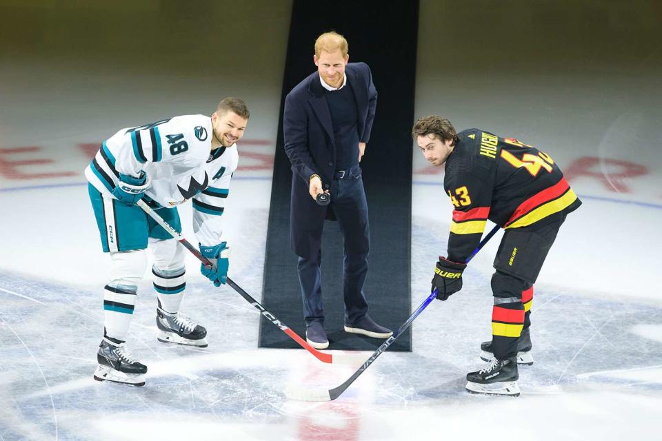 <p>Derek Cain/Getty</p> Prince Harry (center) drops the a ceremonial puck between Quinn Hughes #43 of the Vancouver Canucks and Tomas Hertl #48 of the San Jose Sharks