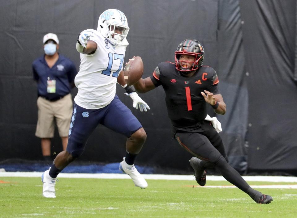 Miami quarterback D'Eriq King (1) is chased by North Carolina linebacker Chris Collins (17) during the first half of an during an NCAA college football game at Hard Rock Stadium In Miami Gardens, Fla, Saturday, Dec, 12, 2020. (Al Diaz/Miami Herald via AP)