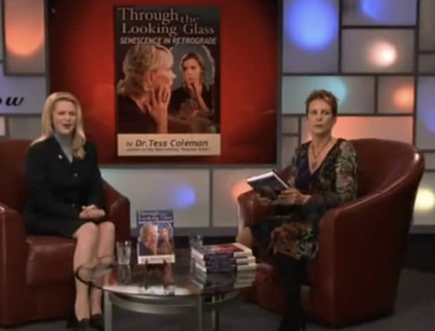 a couple of women sitting on a couch with a table and a poster