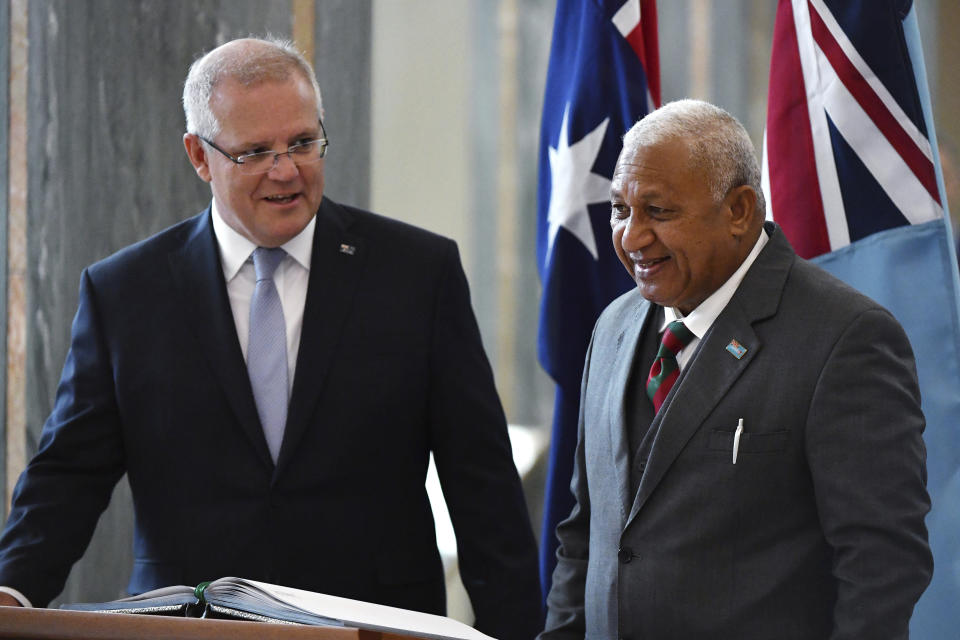 Australia's Prime Minister Scott Morrison, left, watches as Fiji's Prime Minister Voreqe Bainimarama signs the visitors book after an official welcome ceremony at Parliament House in Canberra, Monday, Sept. 16, 2019. (Mick Tsikas/Pool Photo via AP)