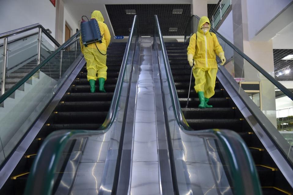 Employees spray disinfectant as part of preventive measures against Covid-19 at the Pyongyang Children’s Department Store in March 2022 (AFP via Getty)