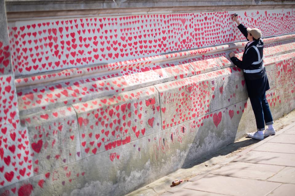 A volunteer adds hearts to the Covid memorial wall in Westminster (PA Wire)