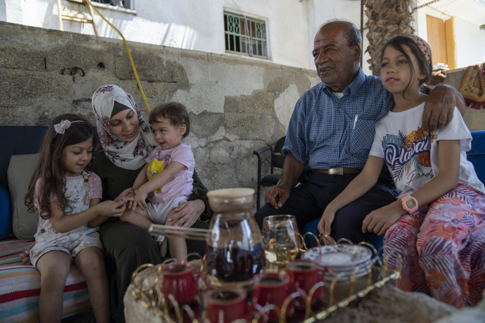 Family members of Khalil Awawdeh, a Palestinian prisoner in Israel, from right, Tolin, 9, Father Mohammad, 63, Maryam 21 months, wife Dalal, 32, and Maria, 4, gather in the garden of their house, in the West Bank village of Idna, Hebron, Tuesday, Aug. 9, 2022. Awawdeh who has refused food for 150 days and is wasting away in an Israeli jailhouse infirmary has suddenly been thrust at the center of efforts to firm up a Gaza cease-fire. (AP Photo/Nasser Nasser)