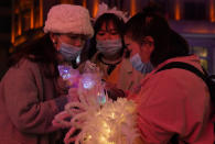 Varias visitantes a una popular calle comercial de Wuhan se apiñan para ver uno de los productos. (AP Photo/Ng Han Guan)