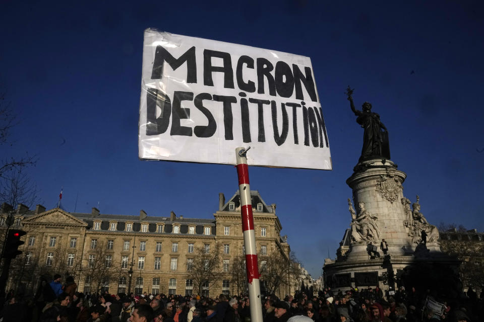 Protesters arrive at Place de la Republique with a placard calling French President Emmanuel Macron to be impeached, during a demonstration against plans to push back France's retirement age, Tuesday, Feb. 7, 2023 in Paris. The demonstration comes a day after French lawmakers began debating a pension bill that would raise the minimum retirement from 62 to 64. The bill is the flagship legislation of President Emmanuel Macron's second term. (AP Photo/Michel Euler)