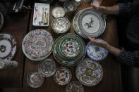 Joseph Tso, owner of Yuet Tung China Works, Hong Kong's porcelain factory, holds a plate with dragon print in Hong Kong, Wednesday, June 8, 2022. Step into Yuet Tung China Works, Hong Kong’s last remaining hand-painted porcelain factory, and you find yourself surrounded by stacks of dinnerware, each piece painstakingly decorated by hand with vibrant motifs of flowers, fruits and animals. (AP Photo/Kin Cheung)