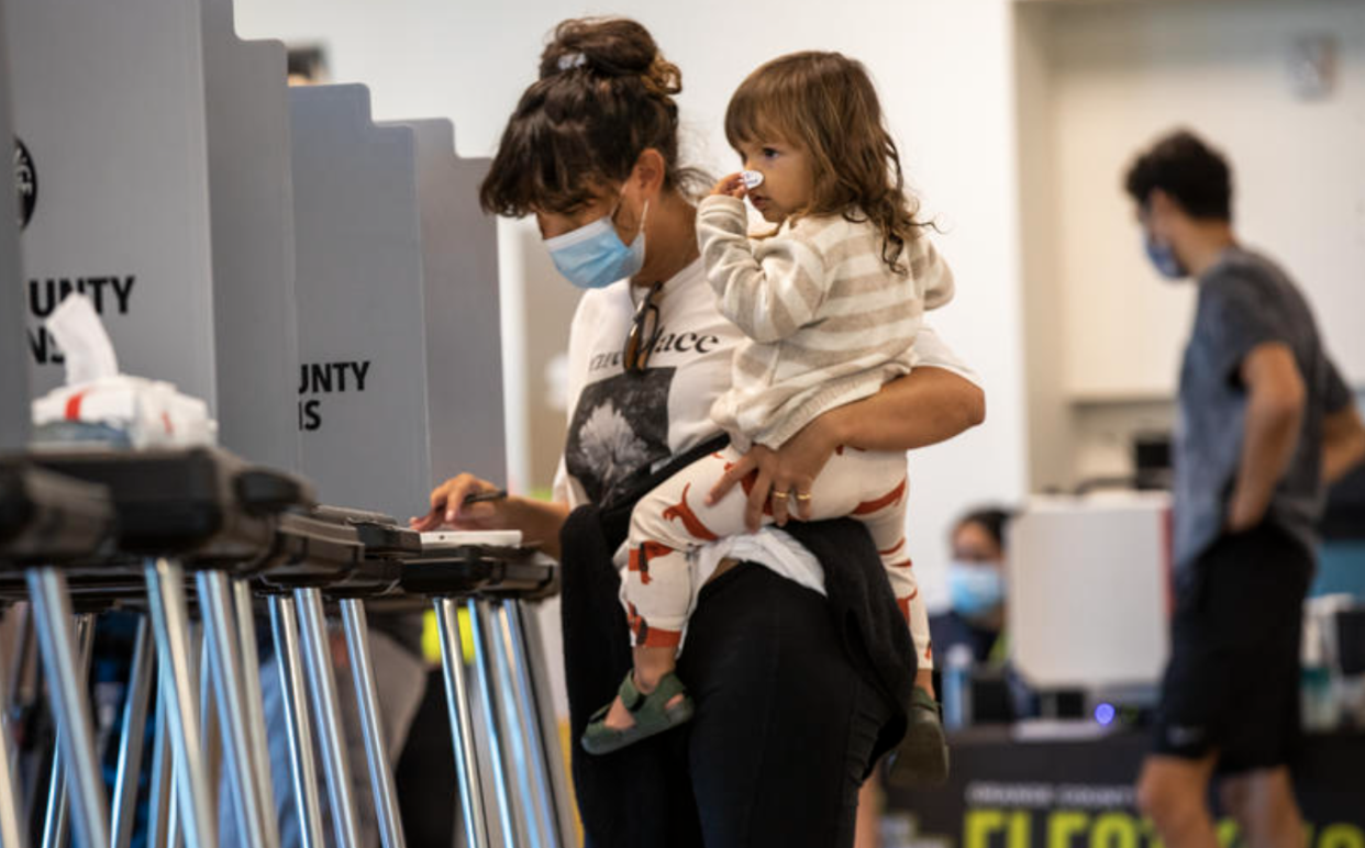 Billie Montague, 2, puts a vote sticker on her nose while watching her mom, Ashley Montague, vote in Newport Beach in 2020.