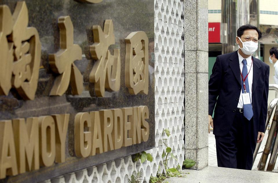 A resident stands outside Amoy Gardens housing estate in Kowloon Bay, Hong Kong, 31 March 2003, where 213 people contracted the deadly pneumonia virus. The government has imposed a ten-day isolation order in a block of the estate where the disease known as severe acute respiratory syndrome (SARS) broke out.  AFP PHOTO/Peter PARKS (Photo by PETER PARKS / AFP) (Photo by PETER PARKS/AFP via Getty Images)