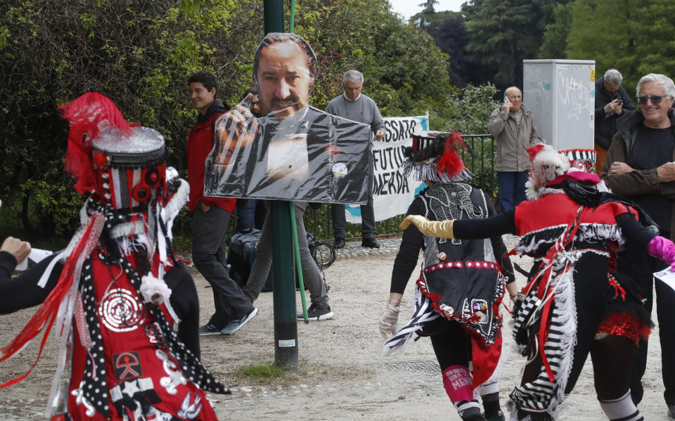 People dance around a portrait of Salvini as they attend a rally to oppose a rally organized by League leader Matteo Salvini, with leaders of other European nationalist parties, ahead of the May 23-26 European Parliamentary elections, in Milan, Italy, Saturday, May 18, 2019. (AP Photo/Antonio Calanni)